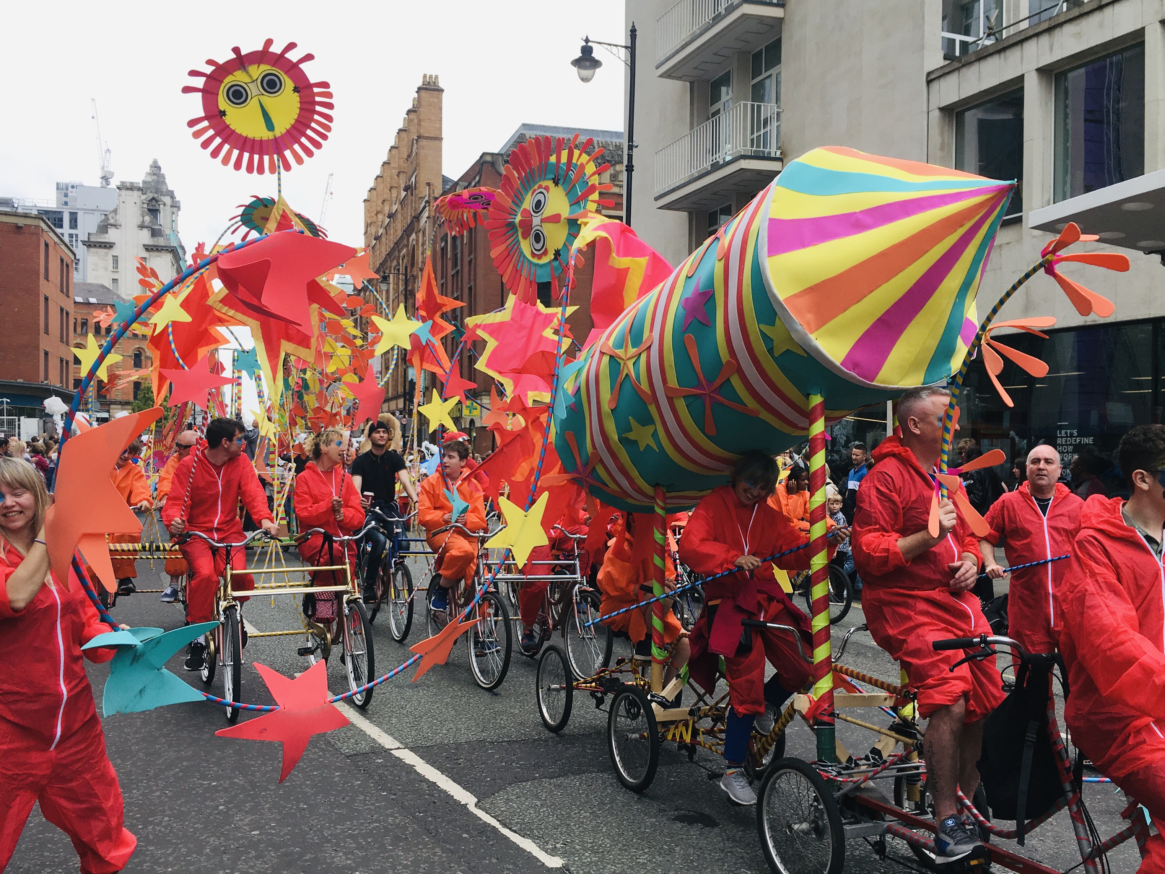 Image: Festival on the streets, group of cyclists moving with a float in the shape of a rocket.